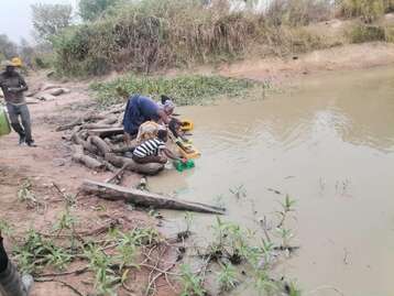 Frauen und Kinder am Wasser Holen an der offenen Wasserstelle